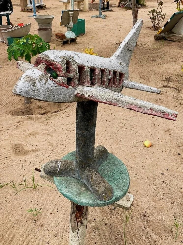Cement airplane sculpture on a pedestal in the yard gallery